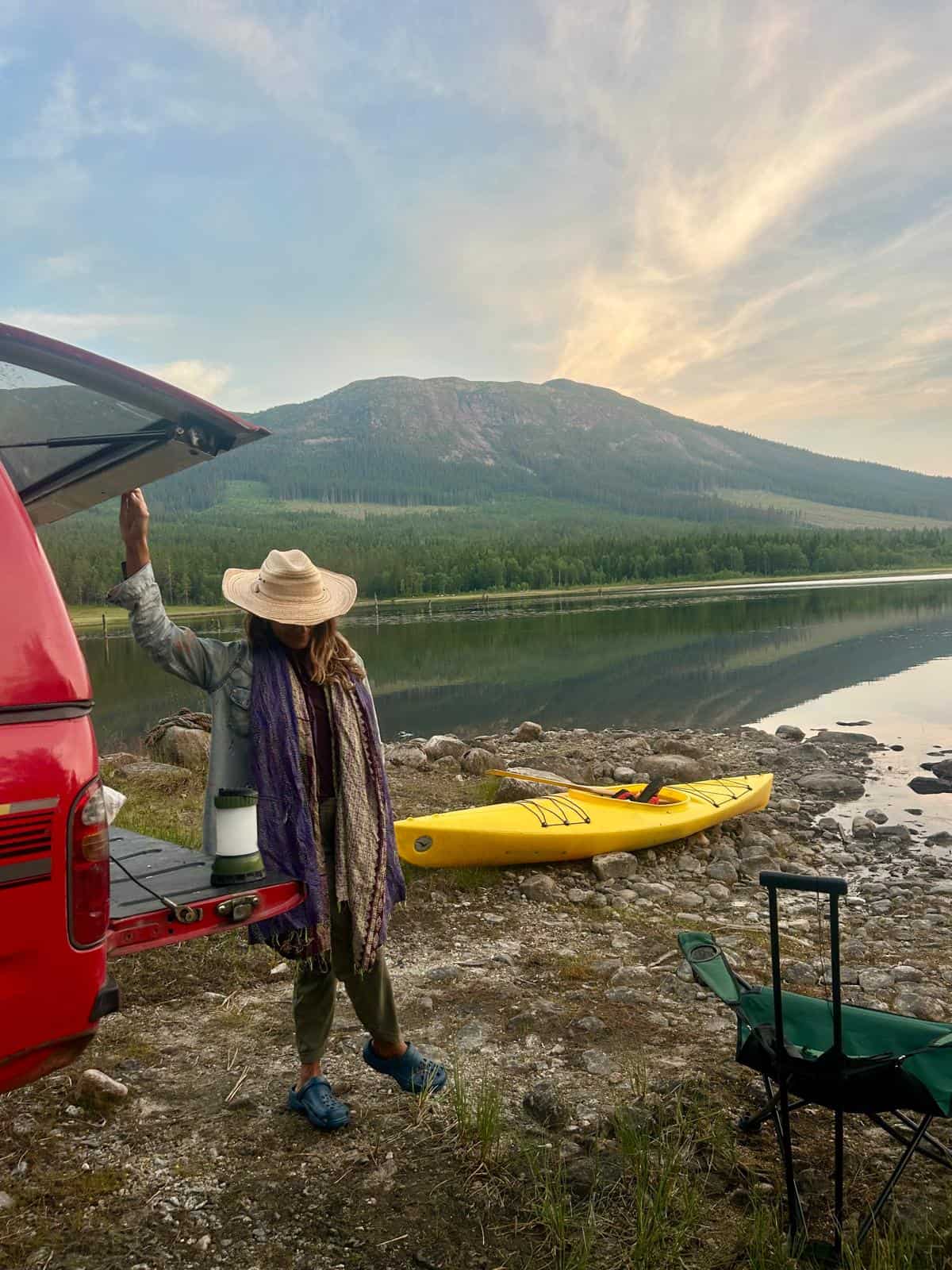 Person preparing kayak by lake with mountain view in background.